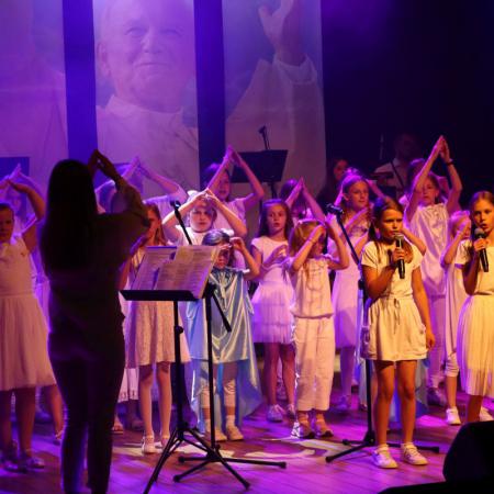 Grupa dzieci śpiewa na koncercie uwielbienia na scenie w RCK