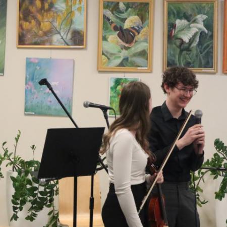 Dziewczyna gra na skrzypcach , obok niej stoi chłopak z mikrofonem