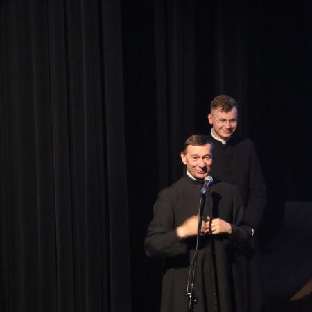 Dwaj księża stoją na scenie i przemawiają do publiczności