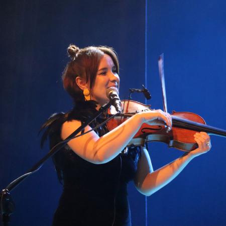 Kobieta z zespołu "KOSY" gra na skrzypcach podczas koncertu