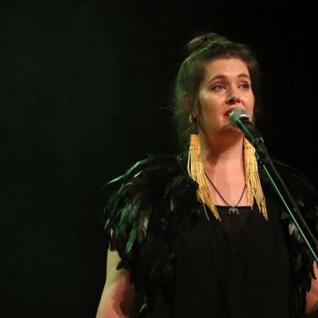 Kobieta z zespołu "KOSY" śpiewa przy mikrofonie podczas koncertu w RCK