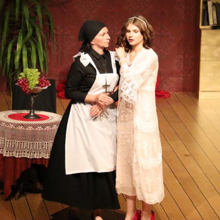 Dwie kobiety występują na scenie podczas sztuki teatralnej "Czapka Błazeńska"