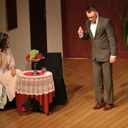 Kobieta i mężczyzna występują na scenie podczas sztuki "Czapka Błazeńska"