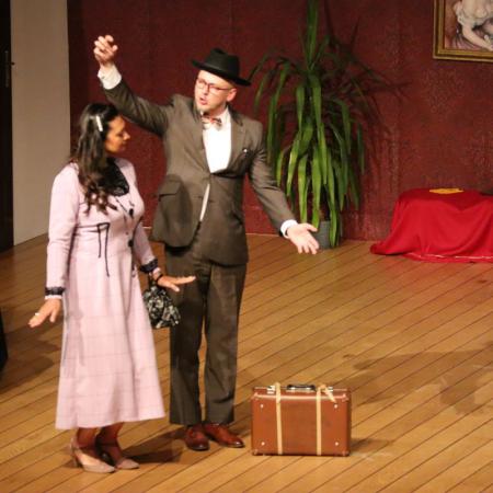 Mężczyzna stoi na scenie z kobietą podczas sztuki teatralnej "Czapka Błazeńska"