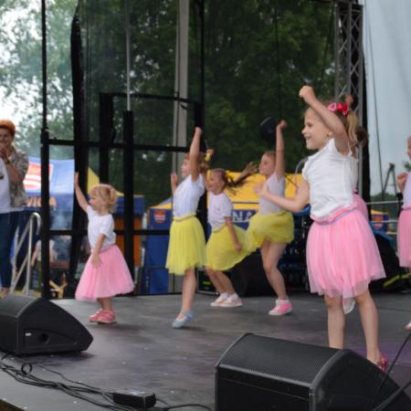 Dzieci w kolorowych spódniczkach tańczą na scenie podczas Sobótki
