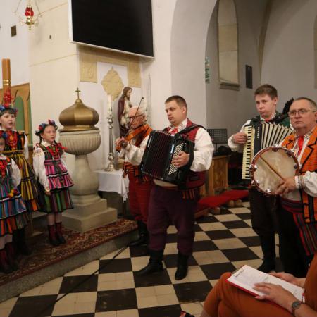 Instrumentaliści z zespołu ludowego grający w kościele przed ołtarzem.