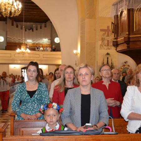 Zaproszeni goście stoją w ławkach na Mszy Św. w Kościele 
