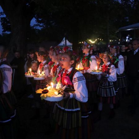 Dziewczynki w strojach ludowych idą z wiankami 