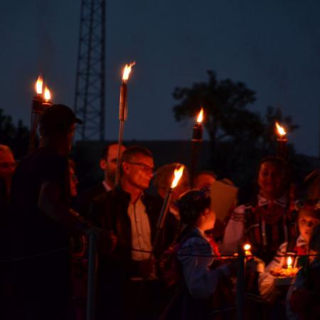 Burmistrz Drzewicy, mężczyźni z pochodniami i dziewczynki w strojach ludowych stoją na molo i śpiewają