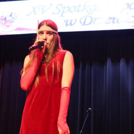 Dziewczyna w czerwonej sukience śpiewa na scenie