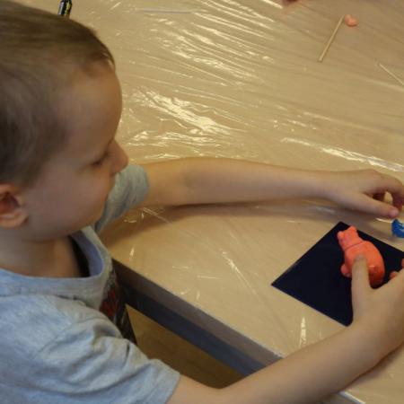 Chłopiec z własnoręcznie ulepioną figurką z masy porcelanowej