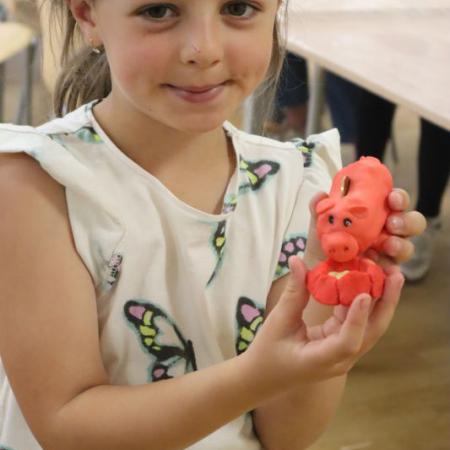 Dziewczynka  pokazuje własnoręcznie wykonana figurkę z masy porcelanowej