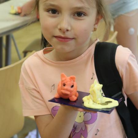 Dziewczynka trzyma w ręce swoją figurkę z masy porcelanowej