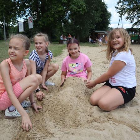 Dziewczyny siedzą na plaży i zasypały koleżankę piaskiem