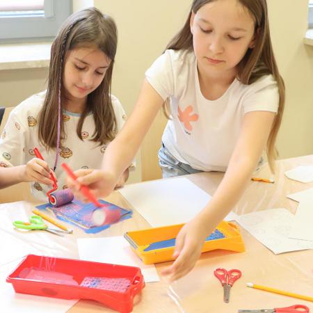 Dziewczynki malują prace plastyczne farbami