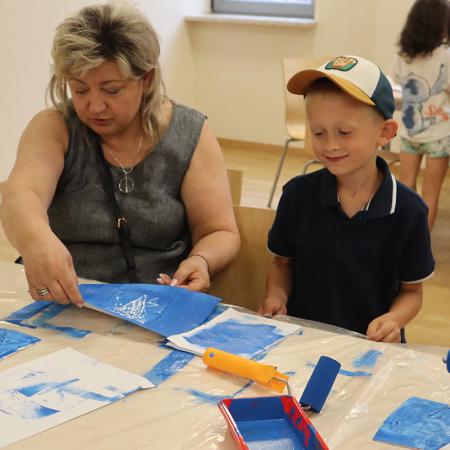 Kobieta pomaga dziecku malować prace plastyczną