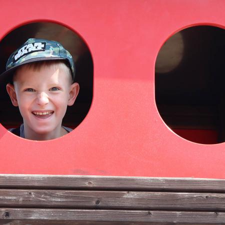 Chłopiec wygląda przez okrągłe okno statku na placu zabaw