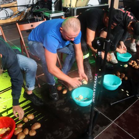 Mężczyźni podczas konkursu obierają ziemniaki.