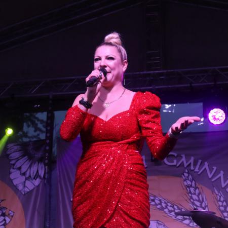 Kobieta w czerwonej sukience śpiewa na scenie