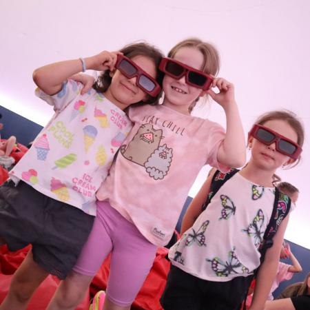 Trzy dziewczynki stoją w okularach w kinie sferycznym