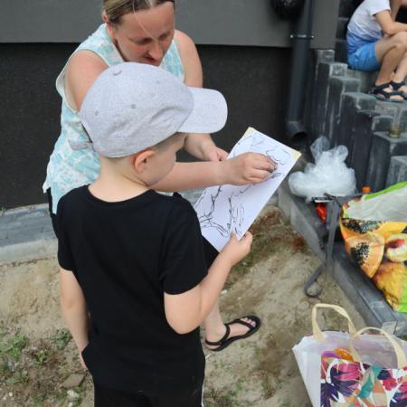 Instruktor zajęć plastycznych pomaga chłopcu narysować obrazek 