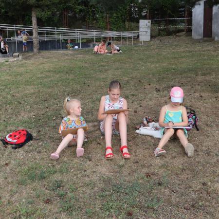 Dziewczyny siedzą na trawniku i rysują obrazy węglem