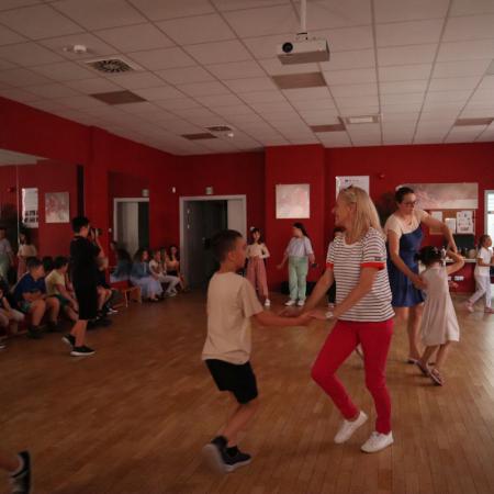 Dzieci oraz instruktorzy zajęć tańczą w parach