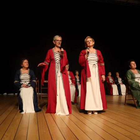 Dwie kobiety w czerwonych sukienkach występują na scenie