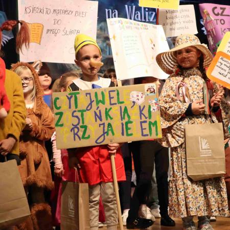 Dzieci w przebraniach z banerami stoją na scenie