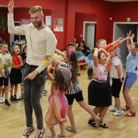Grupa dzieci tańczy razem z instruktorem od muzyki