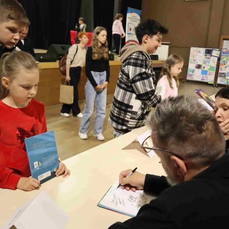 Autor książki daje autograf dziewczynce 