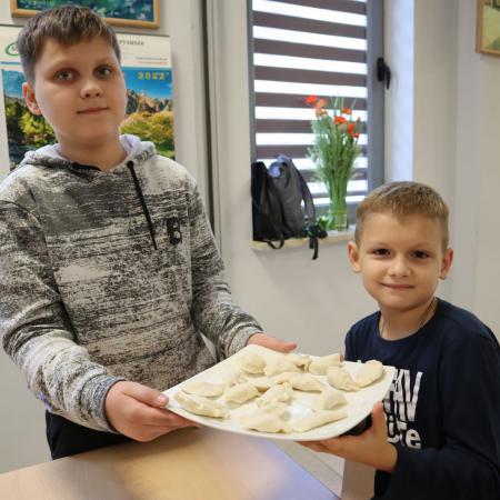Dwóch chłopców trzyma talerz z przygotowanymi pierogami