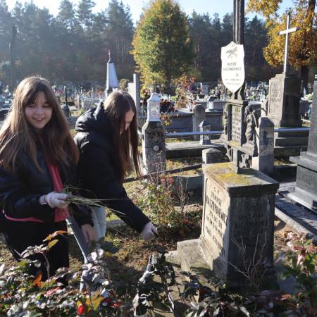Dziewczyny sprzątają zabytkowe groby na cmentarzu w Drzewicy