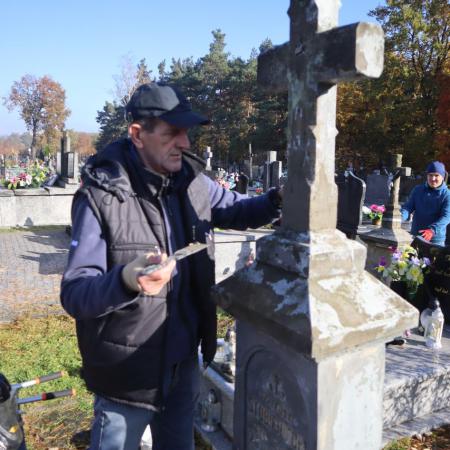 Mężczyzna podczas odnawiania grobu na cmentarzu 