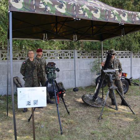 Żołnierze stoją w mundurach pod namiotem na pikniku wojskowym obok RCK