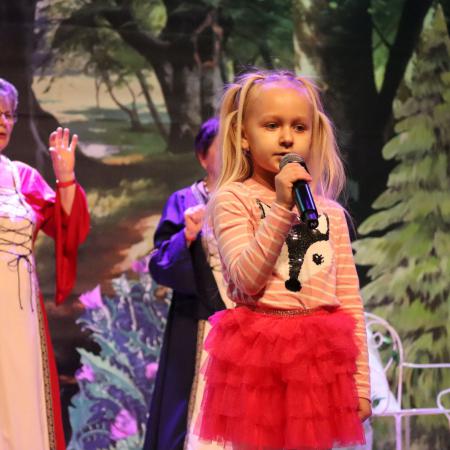 Dziewczynka śpiewa przy mikrofonie podczas Mikołajkowej niespodzianki w RCK