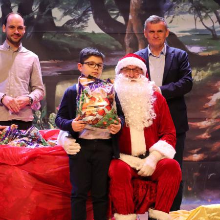 Burmistrzowie Drzewicy wraz z Mikołajem wręczają prezent chłopczykowi 