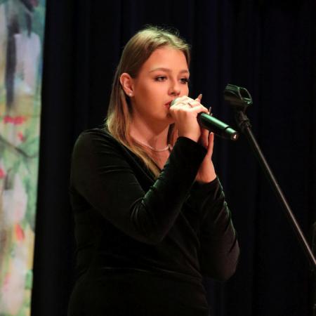 Dziewczyna śpiewa na scenie przy mikrofonie podczas koncertu dla Ukrainy
