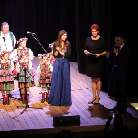 Sekretarz Gminy Drzewica, wraz Dyrektor RCK, Khrystyną Matvienko i dziećmi stoją na scenie podczas koncertu dla Ukrainy