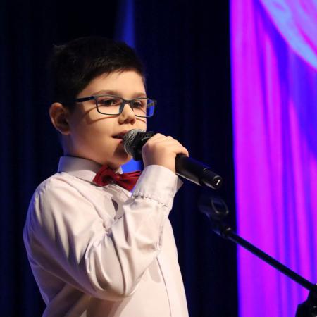 Chłopiec śpiewa przy mikrofonie na scenie