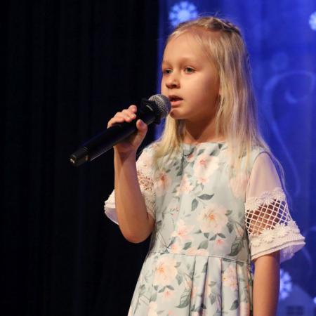 Dziewczynka śpiewa przy mikrofonie na scenie
