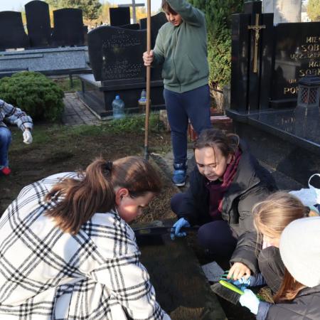 Dziewczynki z SP w Drzewicy porządkują groby na cmentarzu w Drzewicy