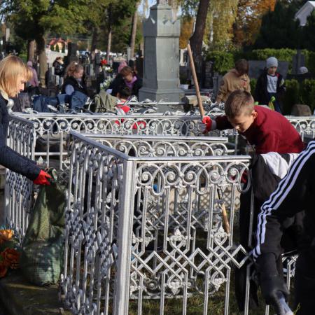 Młodzież porządkuje groby na cmentarzu