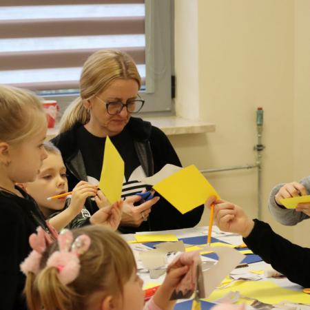 Instruktor Marta Szymańska wykonuje prace plastyczne razem z dziećmi uczestniczącymi w zajęciach
