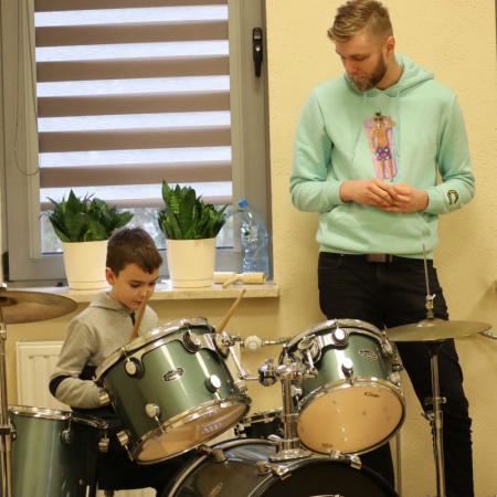 Chłopiec gra na perkusji podczas zajęć muzycznych