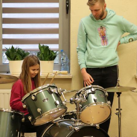 Dziewczynka uczy się gry na perkusji podczas zajęć muzycznych