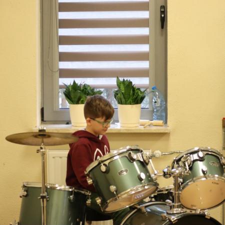 Chłopiec wystukuje rytm na perkusji podczas zajęć muzycznych