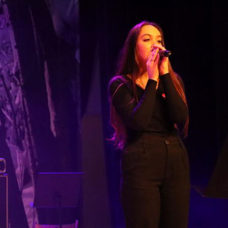 Dziewczyna śpiewa przy mikronie na scenie podczas WOŚP