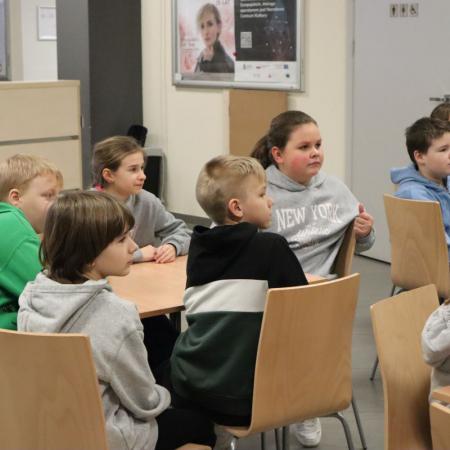 Uczniowie siedzą przy stolikach na warsztatach do wystawy "Sztuka okopowa"