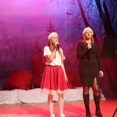 Dziewczyna w czerwonej spódnicy śpiewa z dziewczyną ubraną na czarno 